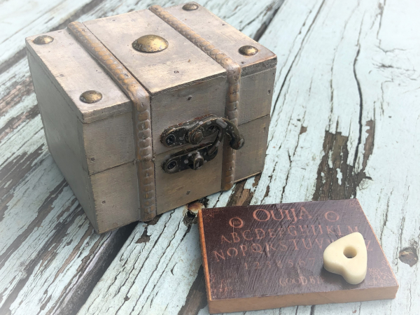 Miniature treasure chest with wood Ouija board and planchette inside mirror